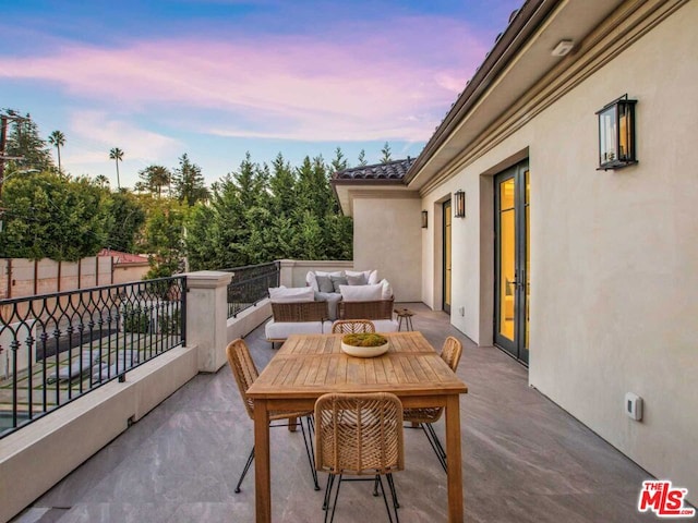 patio terrace at dusk featuring a balcony and an outdoor hangout area