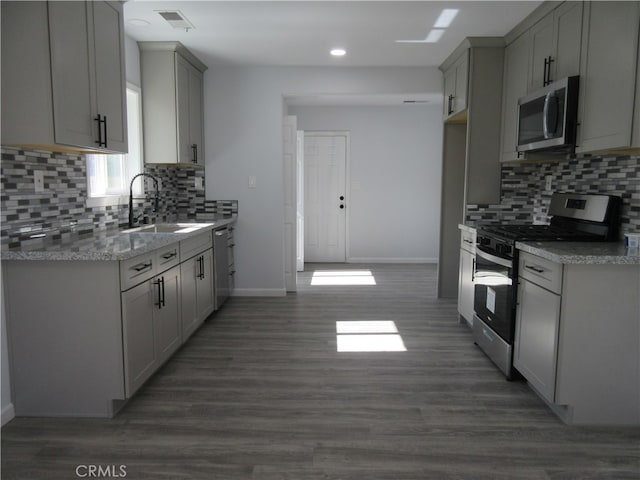 kitchen featuring light stone countertops, dark hardwood / wood-style floors, sink, gray cabinets, and stainless steel appliances