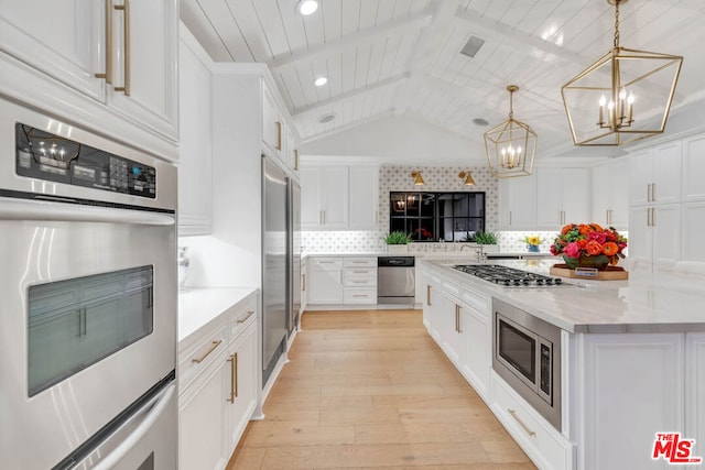 kitchen featuring built in appliances, white cabinetry, hanging light fixtures, and vaulted ceiling