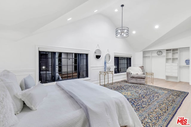 bedroom with hardwood / wood-style floors, high vaulted ceiling, and a chandelier