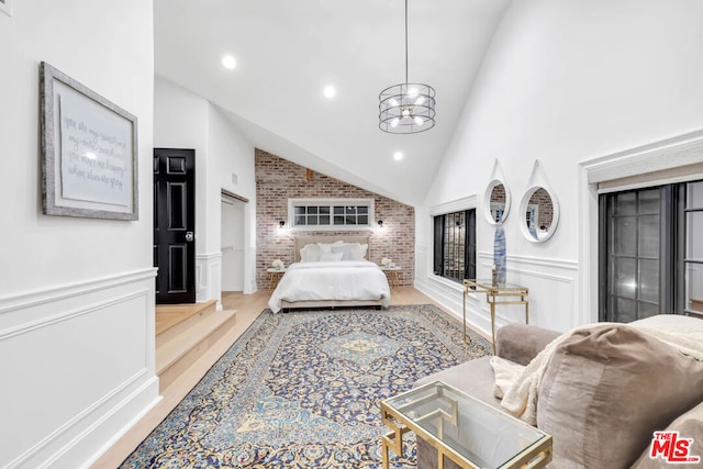 bedroom with a chandelier, hardwood / wood-style flooring, and high vaulted ceiling