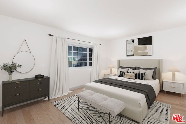 bedroom with light hardwood / wood-style floors and radiator heating unit