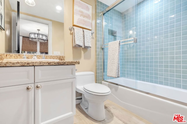 full bathroom featuring a chandelier, vanity, bath / shower combo with glass door, and toilet