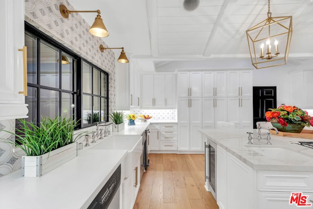 kitchen with sink, hanging light fixtures, light stone counters, light hardwood / wood-style flooring, and white cabinets