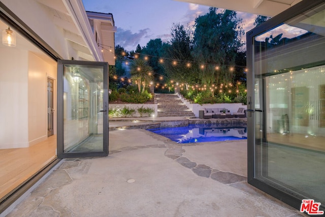 pool at dusk featuring a patio