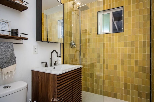 bathroom featuring toilet, vanity, and tiled shower