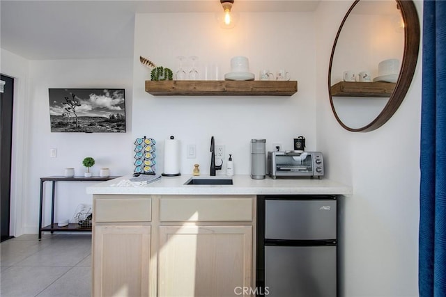 bar with light tile patterned flooring, stainless steel fridge, and sink