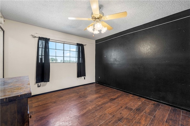 spare room with a textured ceiling, dark wood-type flooring, and ceiling fan