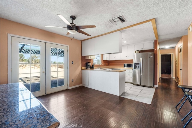 kitchen featuring appliances with stainless steel finishes, white cabinetry, a healthy amount of sunlight, and hardwood / wood-style floors