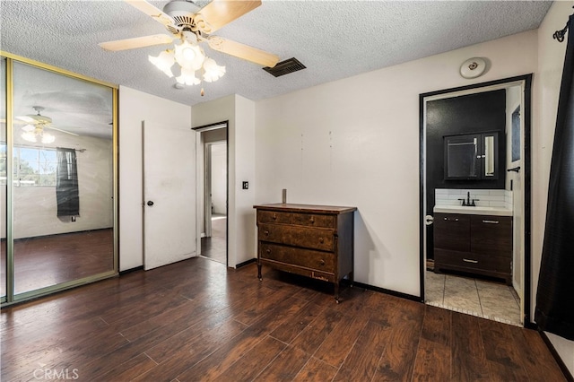 bedroom with ceiling fan, a textured ceiling, wood-type flooring, a closet, and sink