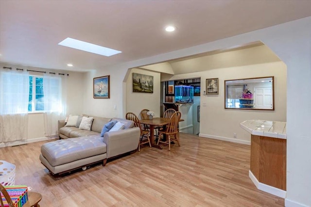 living room featuring a skylight and light hardwood / wood-style floors