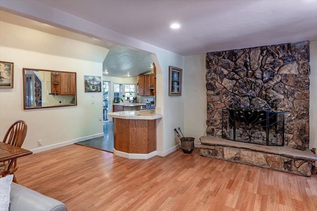 bar with light hardwood / wood-style flooring, tile counters, and a stone fireplace