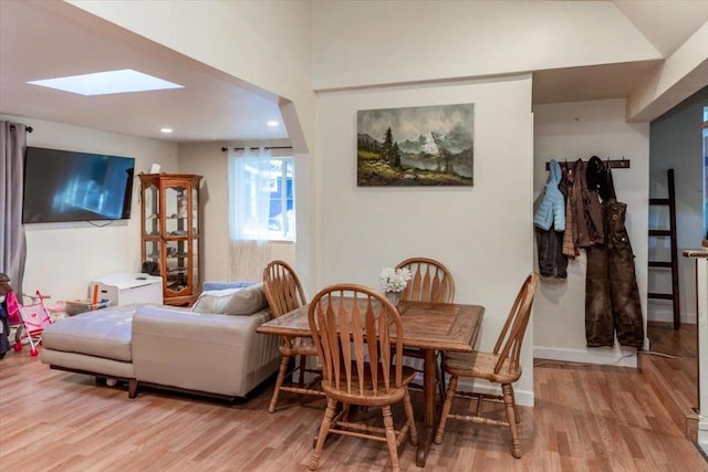 dining area with light wood-type flooring and a skylight