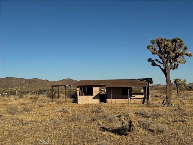 view of front of home with an outdoor structure, a mountain view, and a rural view