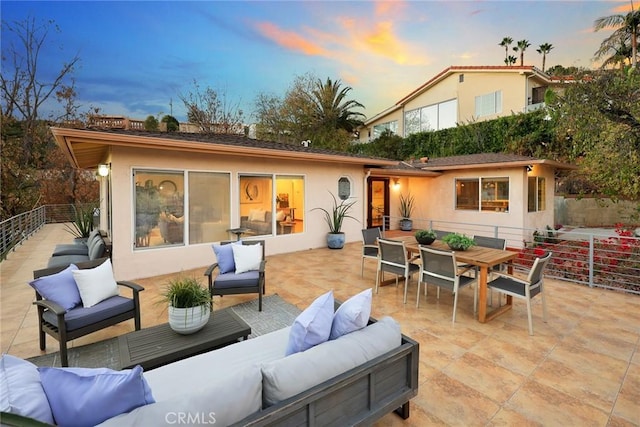 back house at dusk with outdoor lounge area and a patio area