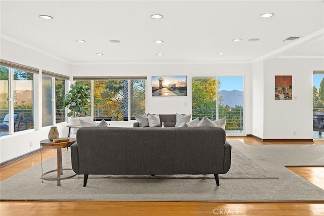 living room with plenty of natural light, ornamental molding, and light hardwood / wood-style flooring