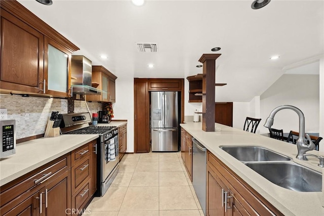 kitchen with appliances with stainless steel finishes, backsplash, sink, wall chimney range hood, and light tile patterned flooring