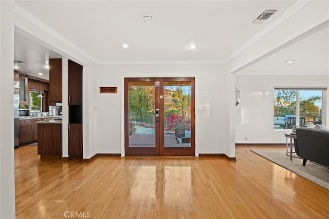 entryway with crown molding, light hardwood / wood-style flooring, and french doors