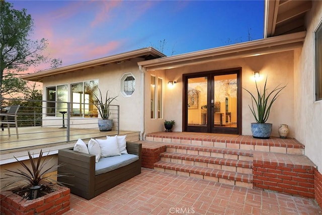 exterior entry at dusk featuring french doors and a patio