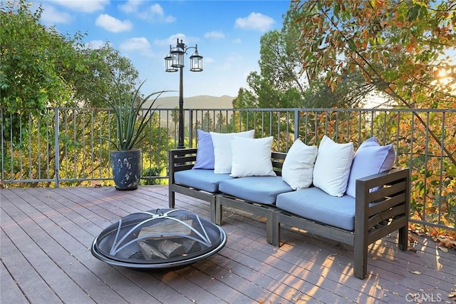 wooden deck featuring a mountain view and an outdoor living space with a fire pit