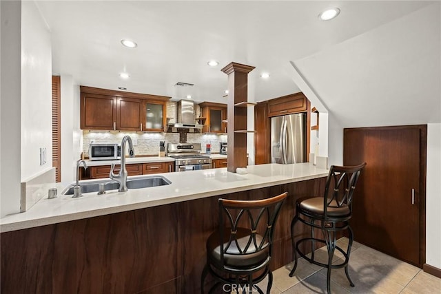 kitchen with kitchen peninsula, appliances with stainless steel finishes, sink, and exhaust hood