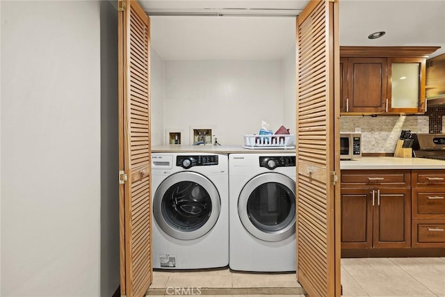 washroom featuring washer and clothes dryer and light tile patterned flooring