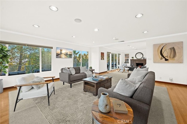 living room featuring crown molding, light hardwood / wood-style floors, and a brick fireplace