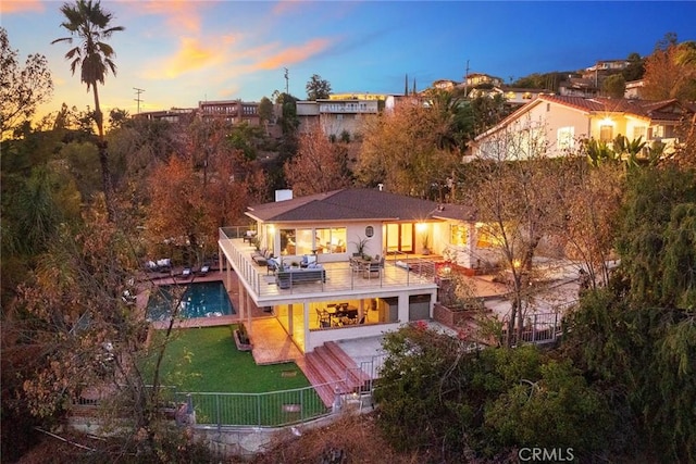 back house at dusk featuring a lawn, an outdoor hangout area, and a patio