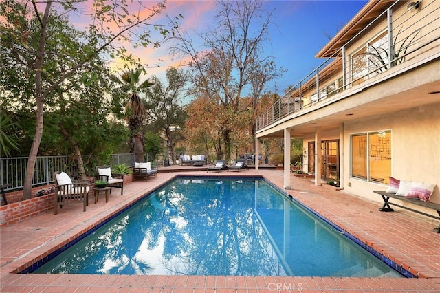 pool at dusk with a patio area