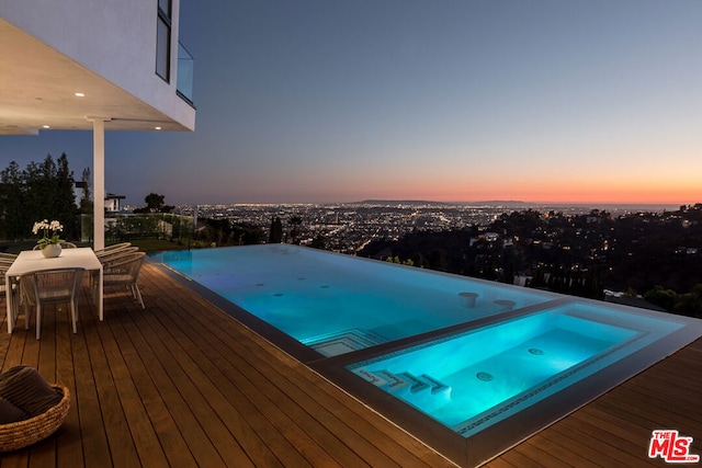 pool at dusk featuring a wooden deck