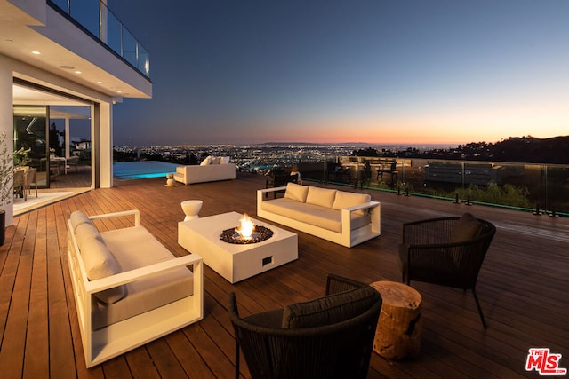 deck at dusk with an outdoor living space with a fire pit