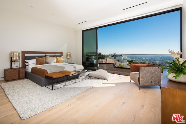 bedroom with hardwood / wood-style floors and expansive windows