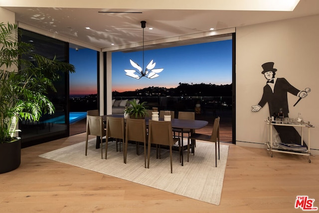 dining area featuring expansive windows, a notable chandelier, and hardwood / wood-style flooring