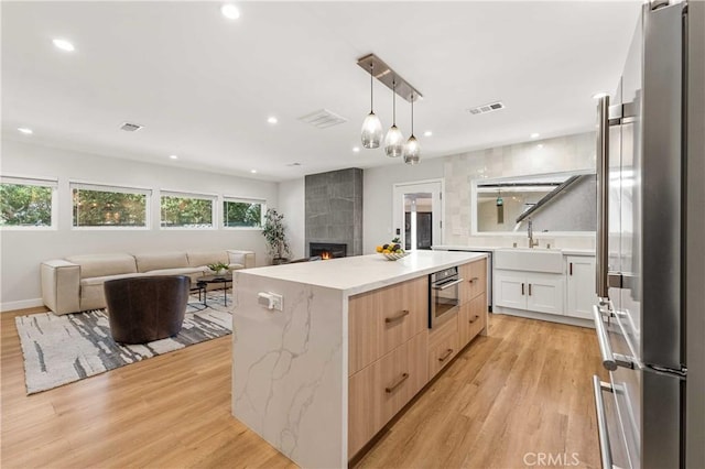 kitchen featuring pendant lighting, a center island, white cabinets, light hardwood / wood-style flooring, and stainless steel appliances