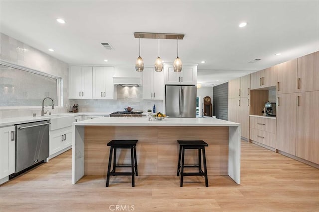 kitchen with a center island, stainless steel appliances, hanging light fixtures, and light hardwood / wood-style flooring