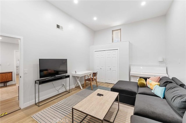 living room with a towering ceiling and light hardwood / wood-style flooring