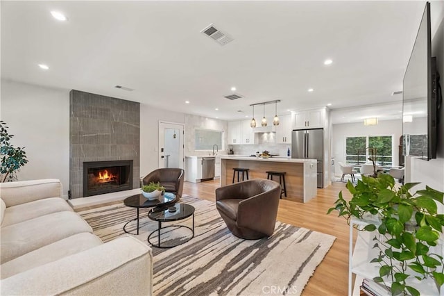 living room with a large fireplace, sink, and light hardwood / wood-style flooring