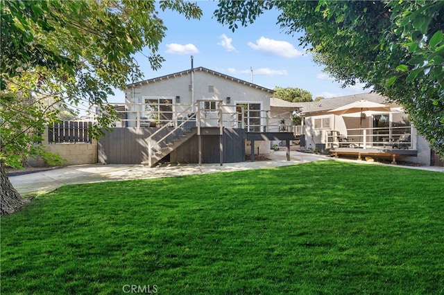 rear view of house with a patio area, a yard, and a wooden deck