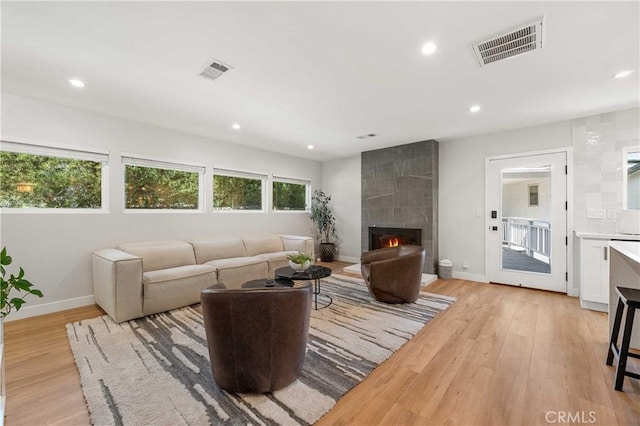 living room featuring a tile fireplace and light hardwood / wood-style floors