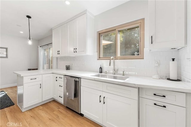 kitchen with sink, hanging light fixtures, light hardwood / wood-style flooring, stainless steel dishwasher, and white cabinetry