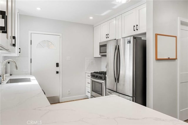 kitchen featuring decorative backsplash, appliances with stainless steel finishes, light stone countertops, and sink