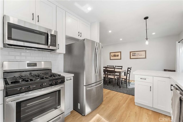 kitchen featuring light stone counters, stainless steel appliances, decorative light fixtures, light hardwood / wood-style flooring, and white cabinets