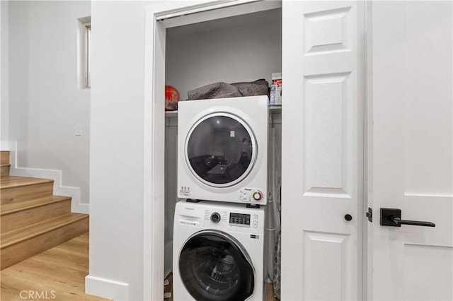 washroom with light hardwood / wood-style flooring and stacked washer / drying machine