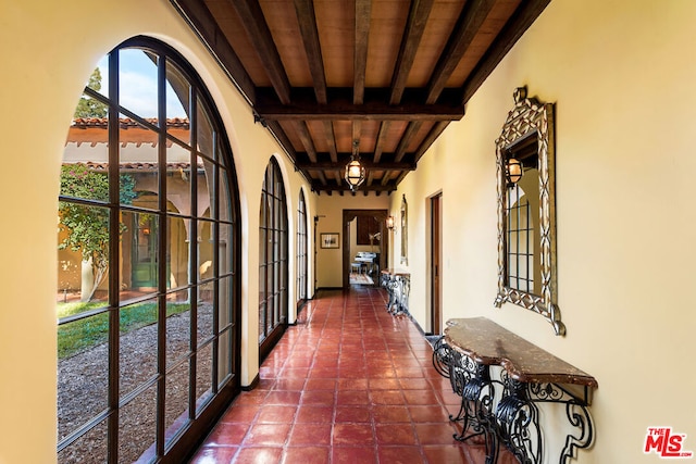 hall with wood ceiling, beam ceiling, and dark tile patterned floors