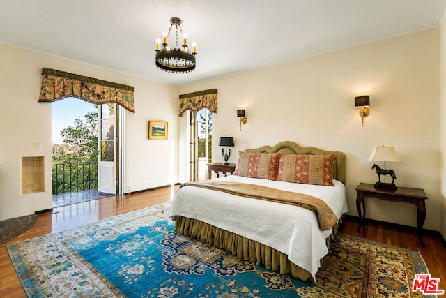 bedroom featuring an inviting chandelier, multiple windows, and hardwood / wood-style floors