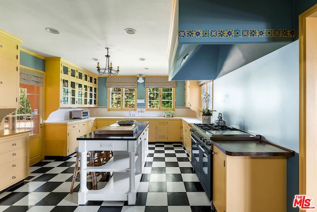 kitchen featuring high end stove, a chandelier, light brown cabinetry, pendant lighting, and a center island