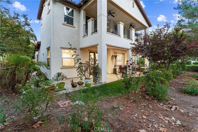 back of property with ceiling fan, a balcony, and central air condition unit