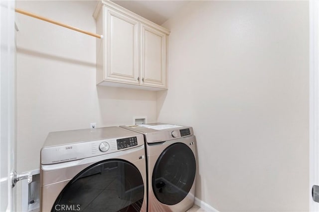 clothes washing area featuring washing machine and clothes dryer and cabinets