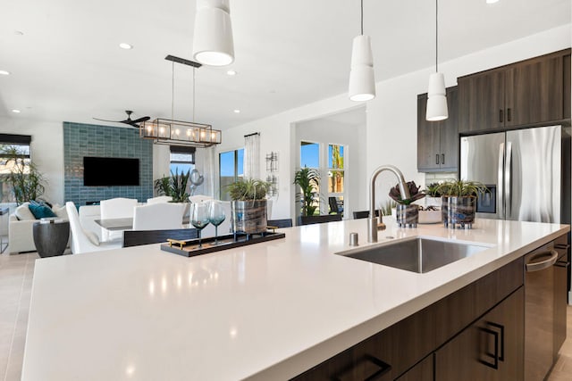 kitchen with sink, stainless steel fridge, dark brown cabinets, and a healthy amount of sunlight