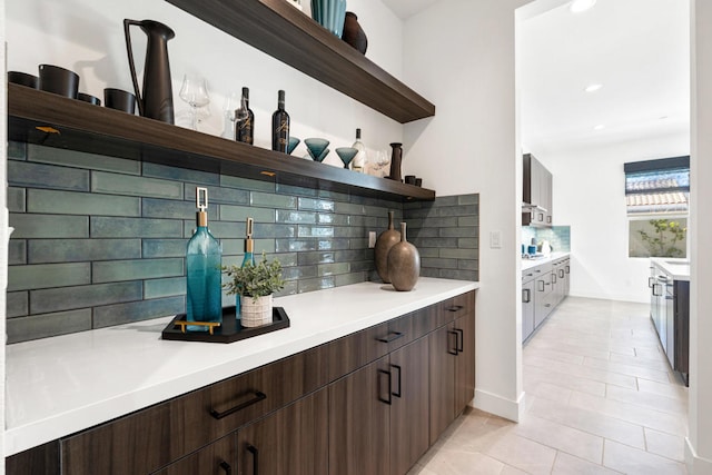 bar featuring light tile patterned floors, dark brown cabinets, and backsplash